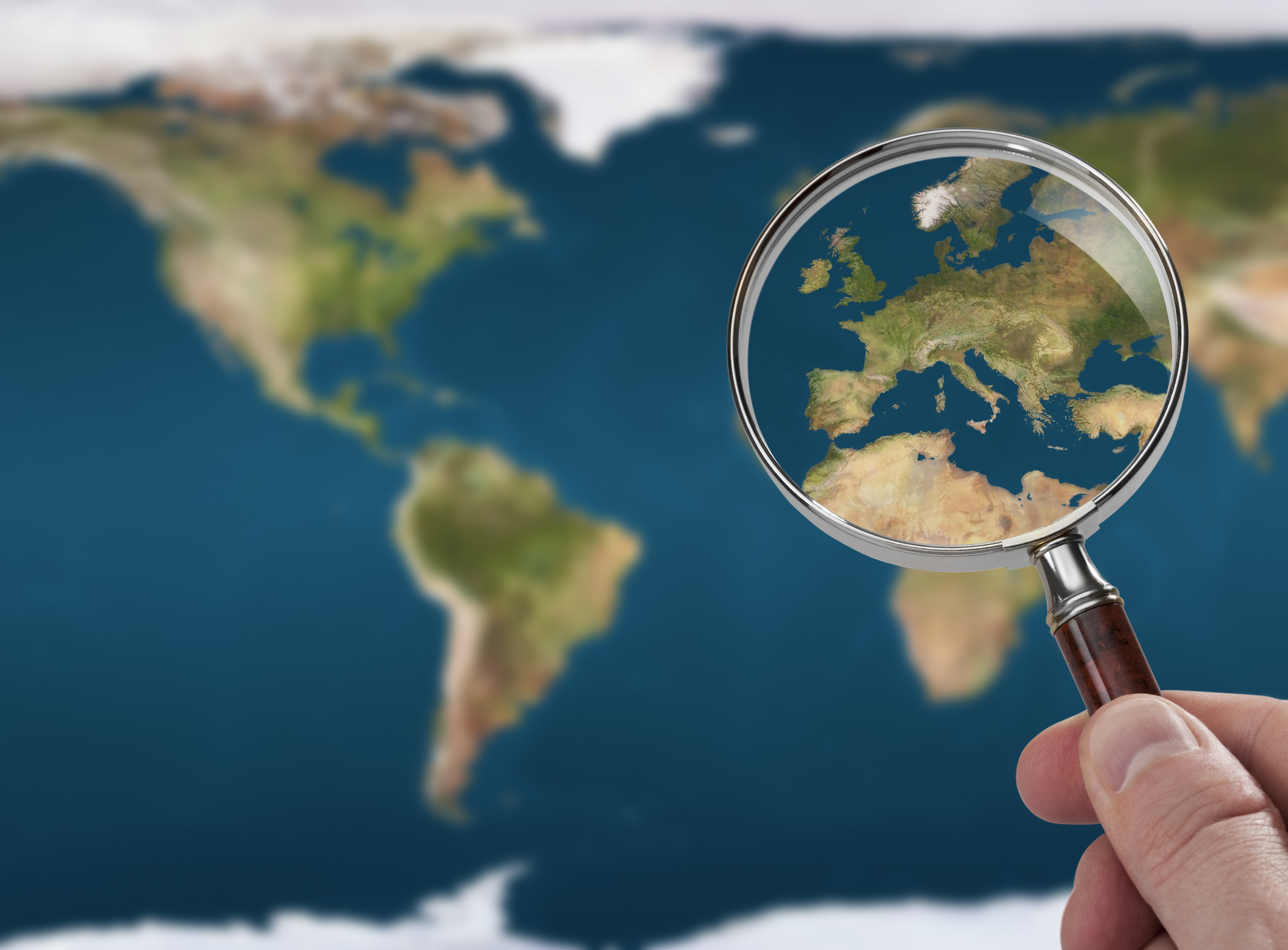 Um mapa mundi sendo observado com uma lupa
